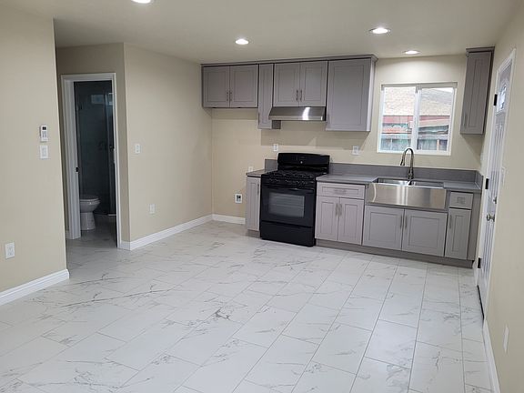 Living room with mini-split air conditioner, and kitchen featuring a gas range, range hood, and a microwave