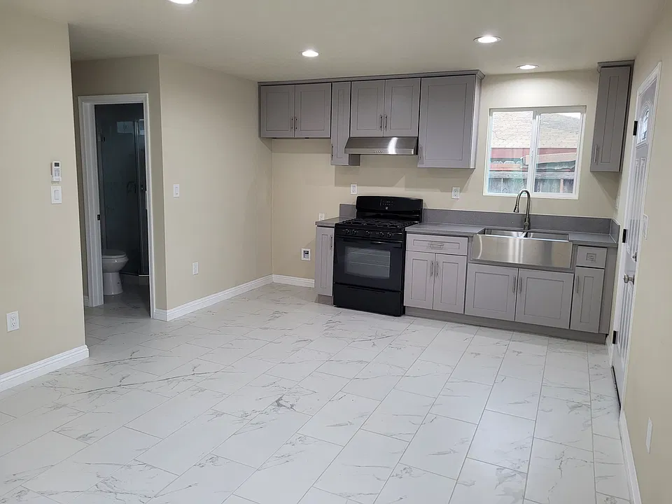 Living room with mini-split air conditioner, and kitchen featuring a gas range, range hood, and a microwave