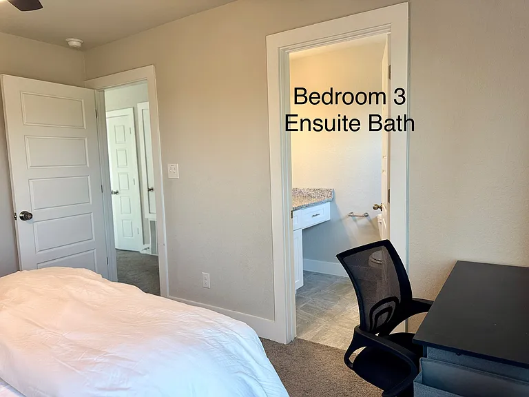 Bedroom 3 with a dedicated desk and a view here to the private ensuite bath for added convenience and privacy.