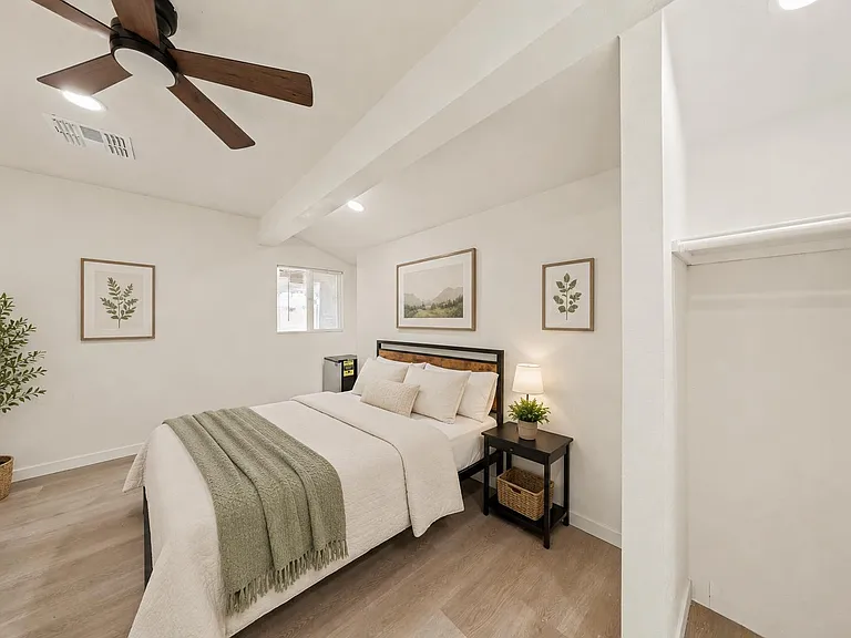 Spacious bedroom with a ceiling fan, wood-look flooring, and a built-in closet plus a nightstand for convenient storage.