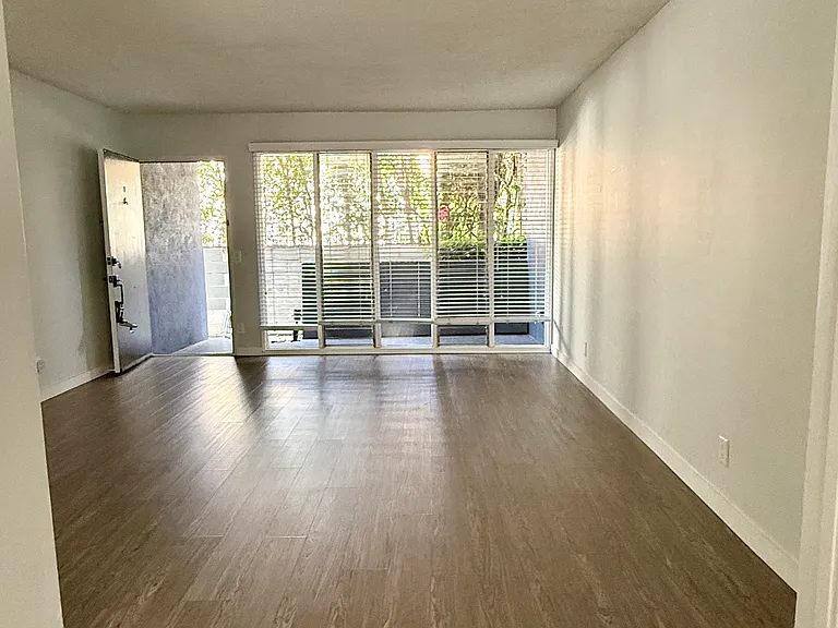 View of the dining room, living room, and front door and patio from the kitchen.