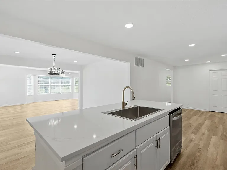 Kitchen featuring a sink, an island with sink, dishwasher, light wood-style flooring, and open floor plan