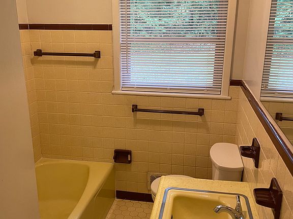 Yes, it's yellow. I said it was vintage. The original soap and toothbrush holders are convenient. And the towel bars are intact. The linen closet is behind the door. The vanity has extra storage and a huge mirror.