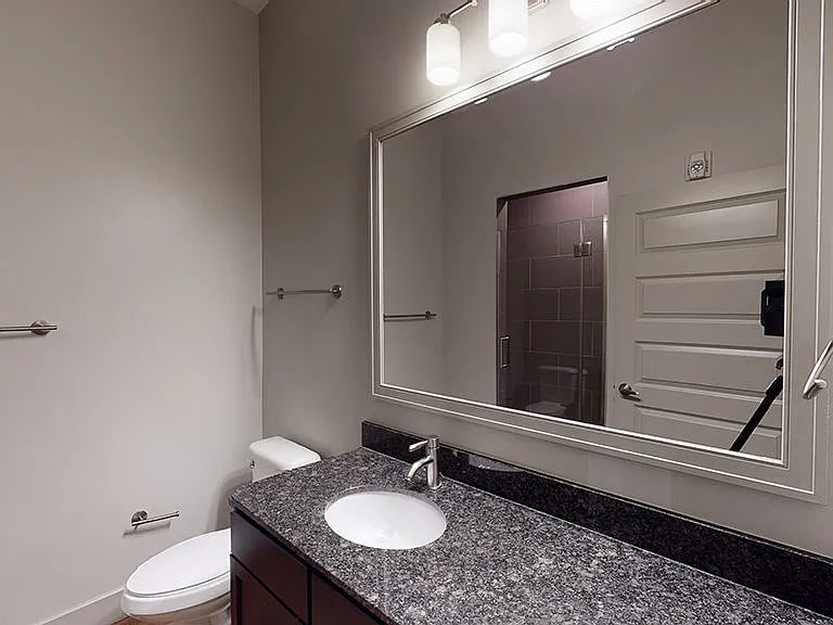 Apartment bathroom with glass enclosed shower and wood-style flooring.