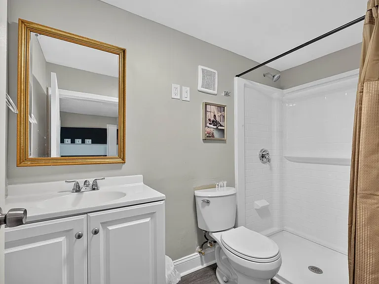 Full bathroom with a vanity sink, framed mirror, and tub/shower combo with tile surround and curtain rod.