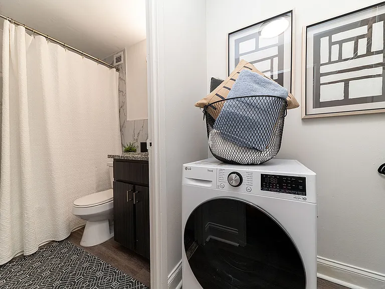 Bright bathroom with granite counters, bathtub, and Laundry area