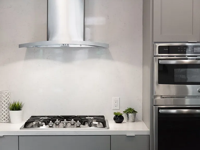 Signature Collection kitchen with light grey cabinetry, quartz stone countertop, stainless steel appliances and ceramic tile backsplash