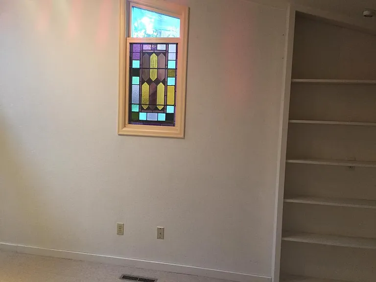 Bedroom, east wall stained glass window and shelves