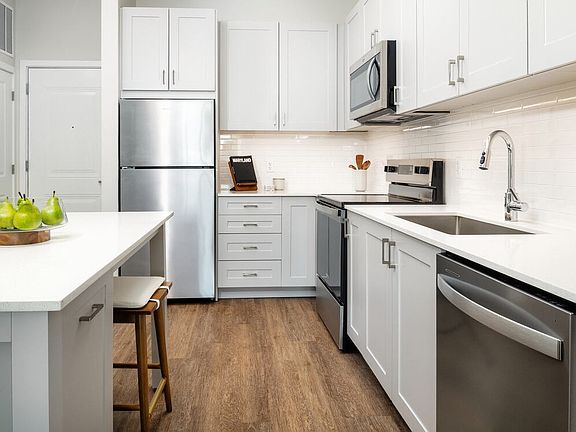 New West Phase - Finish Package III Kitchen with stainless steel appliances, white quartz countertops, grey cabinetry, and hard surface flooring