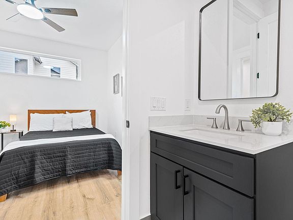 Private bedroom with ceiling fan, wood-look flooring, and a convenient ensuite vanity with generous counter space.