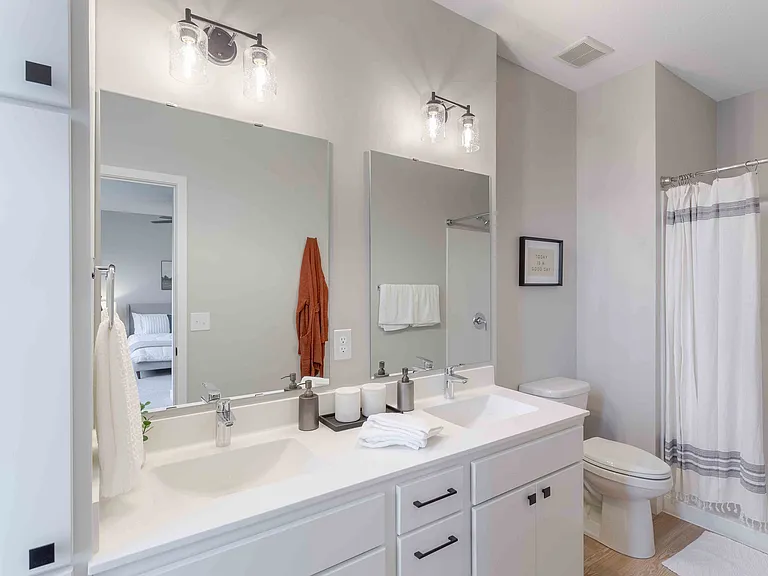 Elegant bathroom featuring dual sinks with modern fixtures, stylish lighting, and a cozy ambiance.