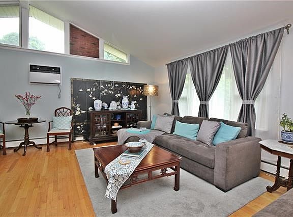 The living room features soaring ceilings, custom windows & brick accented wall.