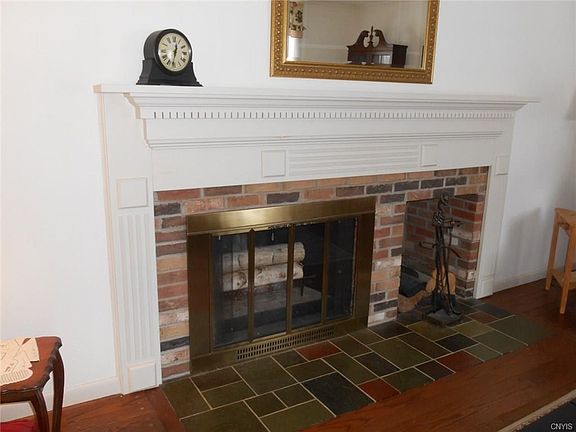The Wood-burning Living Room Fireplace Features a Custom Mantle Accented by Dentil Moulding & Wood Storage