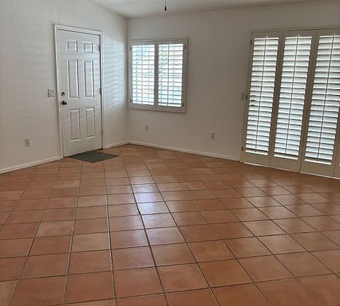 spacious living room has plantation shutters and ceiling fan