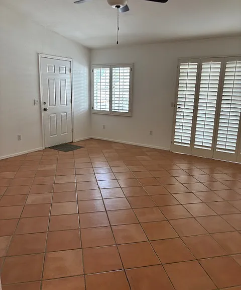 spacious living room has plantation shutters and ceiling fan