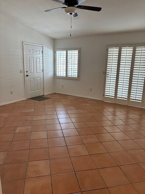 spacious living room has plantation shutters and ceiling fan