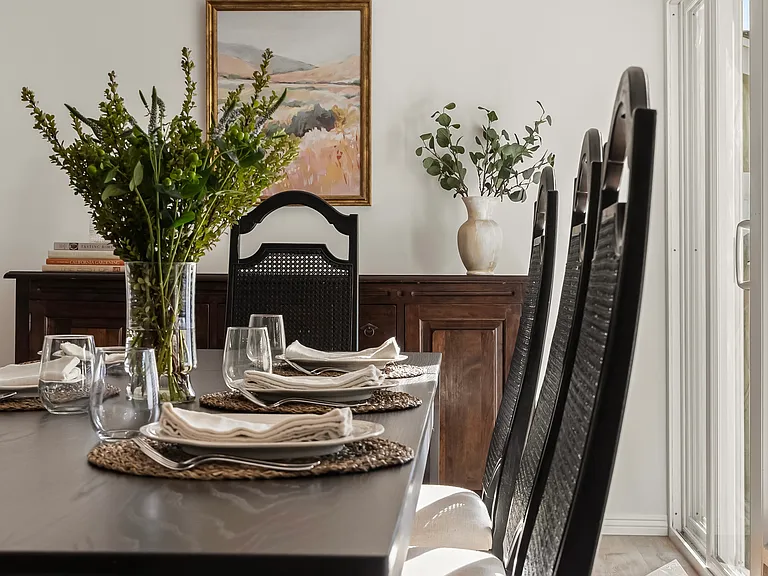 Bright dining area seating eight, seamlessly connecting both living rooms with expansive windows overlooking the backyard.
