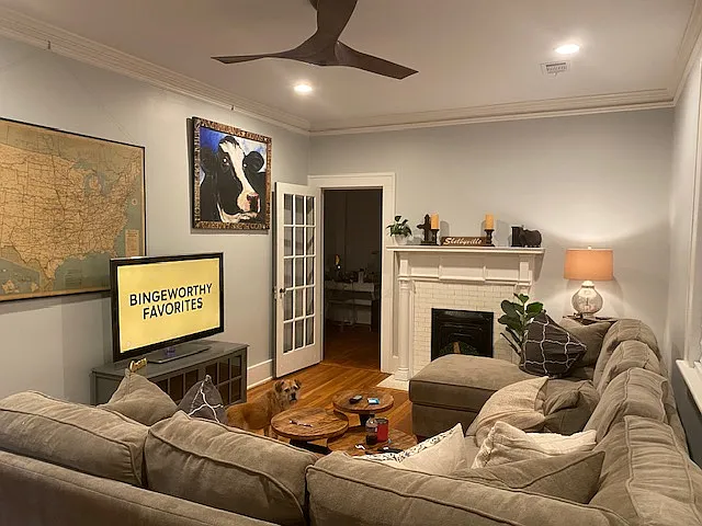 Living room with door leading to sunroom. Crown molding with picture rail for hanging. (2) large windows