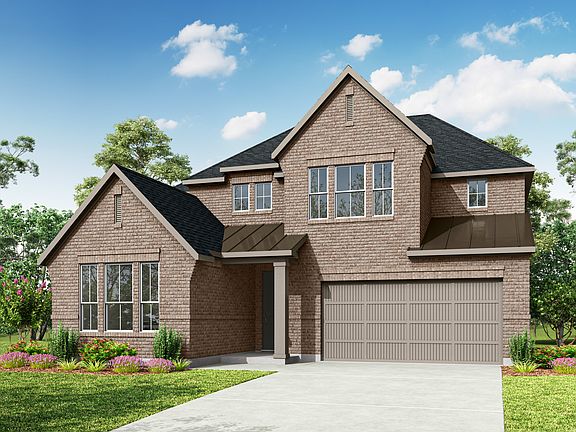 A two-story brick house with a gabled roof, surrounded by lush greenery and a clear blue sky with fl