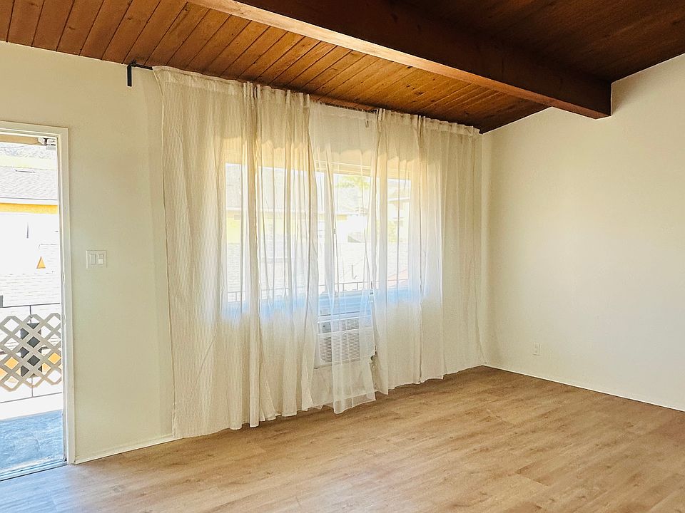 welcome to a large living room with beautiful wood cathedral ceiling, large curtained window, provides natural light, with partial mountain view