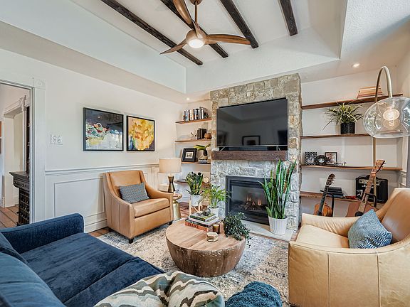 The living room blends warmth and style with a textured stone fireplace and thoughtfully chosen mid-century modern decor.