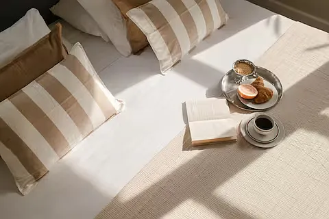 Inviting bedroom with a queen-sized bed and soft linens. Sunlight fills the room, and bedside lamps add warmth and a stylish, relaxed vibe.