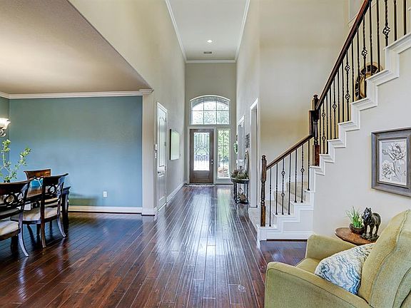 View of the large entry, stair case with iron spindles, and beautiful wood flooring.