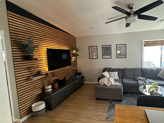 Bright and cozy living room featuring custom-built wooden slat wall and sleek plywood flooring