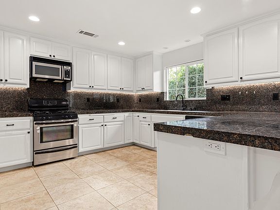 Enormous kitchen with stainless steel appliances, large countertops and under-cabinet lighting.