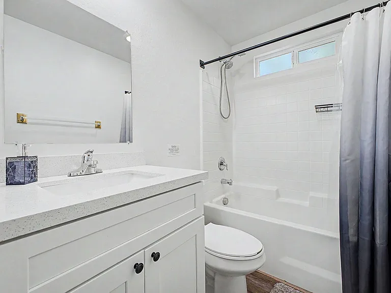 Clean full bath with a spacious vanity, large mirror, and tub/shower combo with tile surround and privacy window.