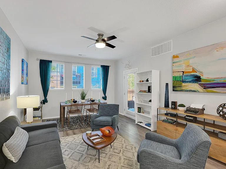 Bright and modern living room with chic decor, featuring cozy seating, a stylish wooden dining table, and vibrant artwork, ideal for both relaxation and entertaining.