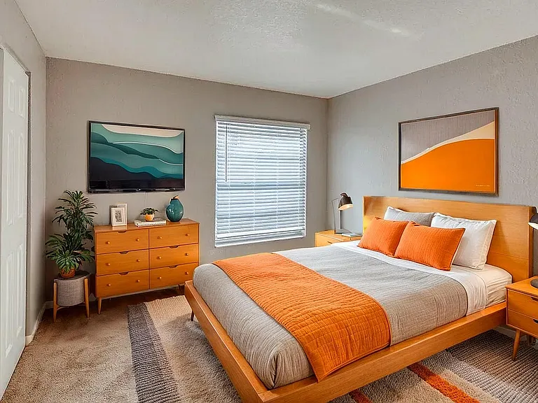 Contemporary bedroom with stylish orange accents, featuring modern wooden furniture and vibrant artwork, perfect for a cozy and chic living space.