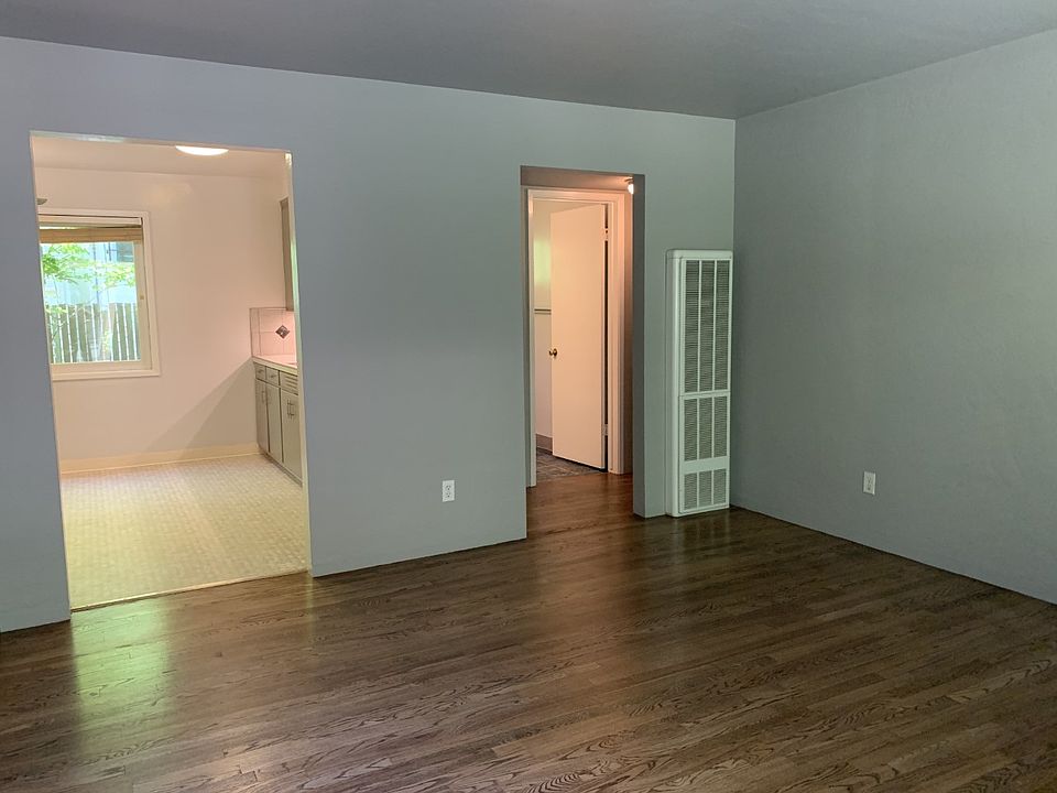 This is a view from the large living room towards the kitchen on the left and the hallway to the bathroom and two bedrooms.
