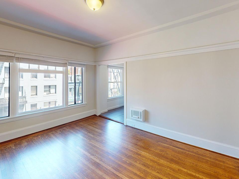 Spacious living room with wood-like flooring and a large window offering natural light