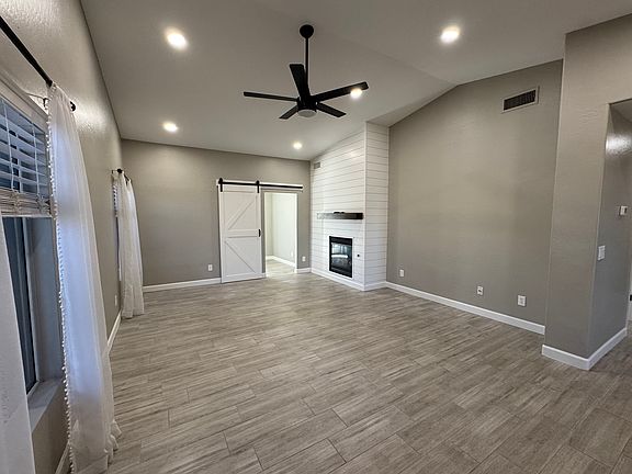 Spacious living room with vaulted ceilings, windows and a cozy gas fireplace complete with a decorative mantle