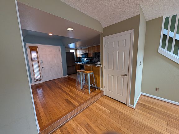 View back towards foyer and kitchen with raised bar + stools