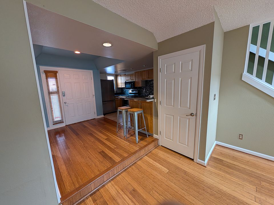 View back towards foyer and kitchen with raised bar + stools
