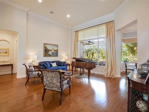 Formal living area with a view of the lush pool area. Hardwood floors throughout the home.