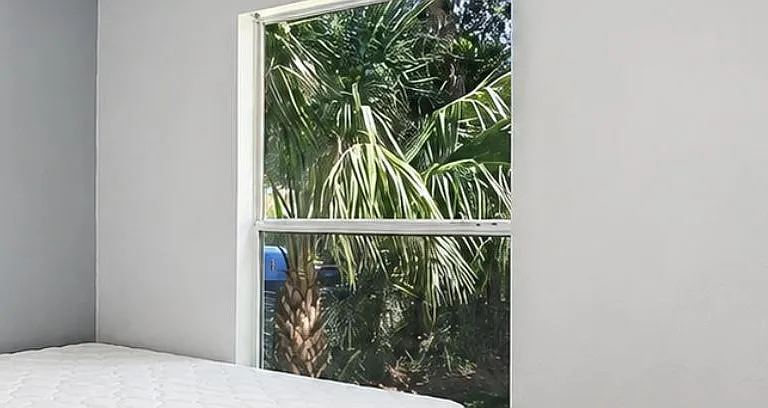Comfortable bedroom with a large window offering leafy outdoor views and plenty of natural light.