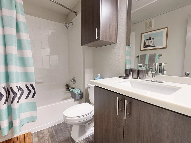 Apartment Bathroom with large soaking tub, vanity mirror and Wood-Style Flooring.