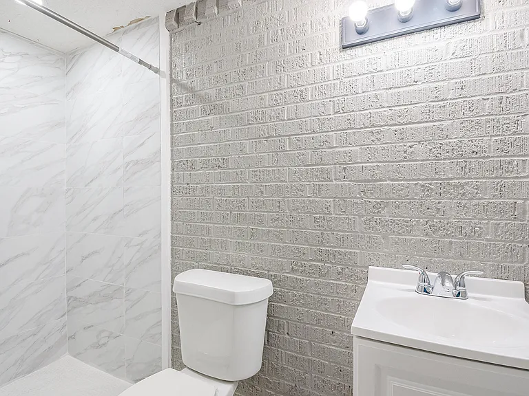 Bathroom features a tiled tub/shower surround, vanity with chrome faucet, and overhead lighting for everyday convenience.