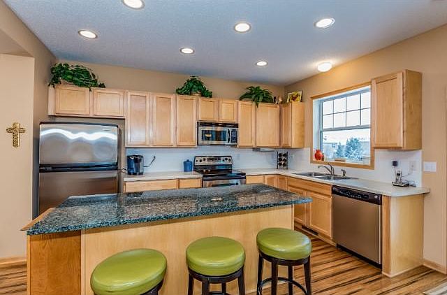 Spacious kitchen with granite center island, stainless steel appliances and maple cabinetry.