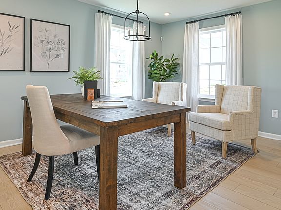 Spacious dining room with 2 large windows on adjacent walls and light colored wood floors
