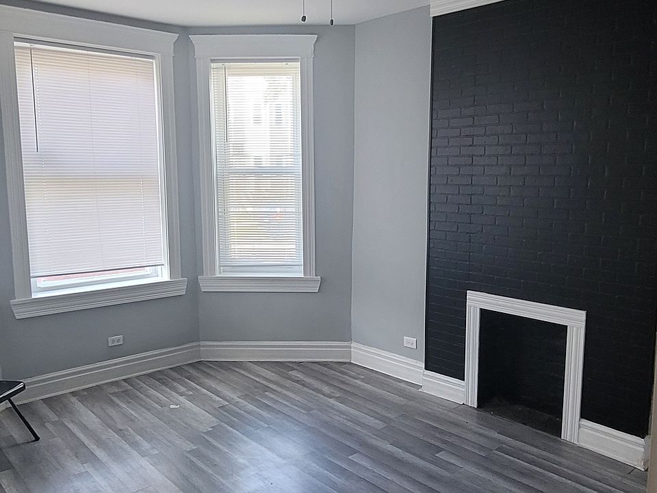 nice size living room with black fireplace & ceiling fan.
