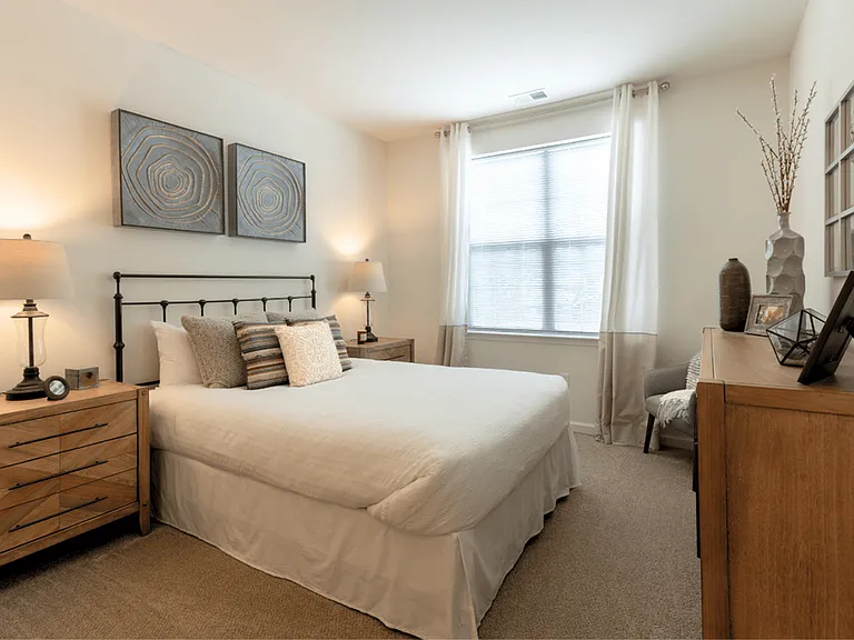 Spacious bedroom in a modern apartment featuring luxury carpeting, ample natural light, and a sleek, contemporary design for a comfortable and stylish retreat.