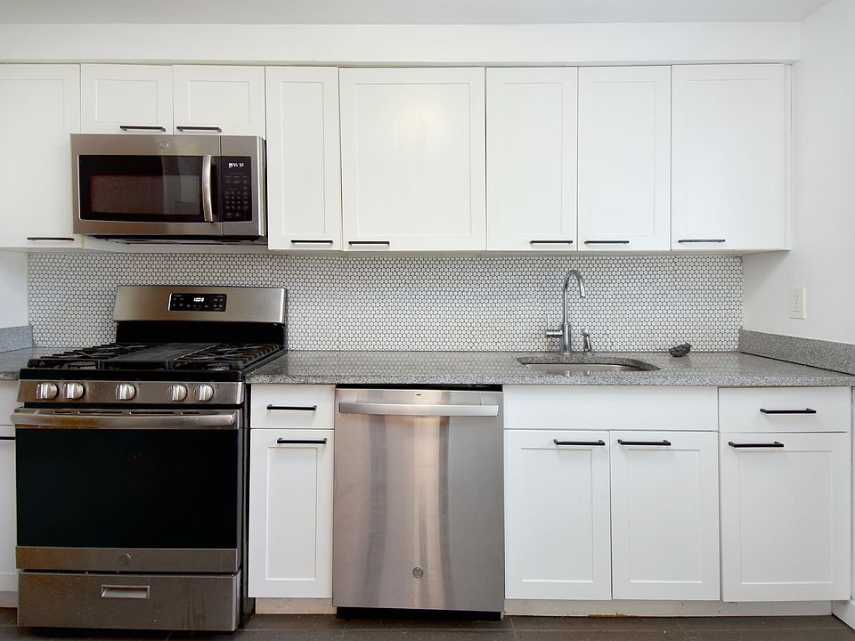Completely renovated kitchen with modern stainless steel appliances, quartz countertops, and mosaic tile backsplash
