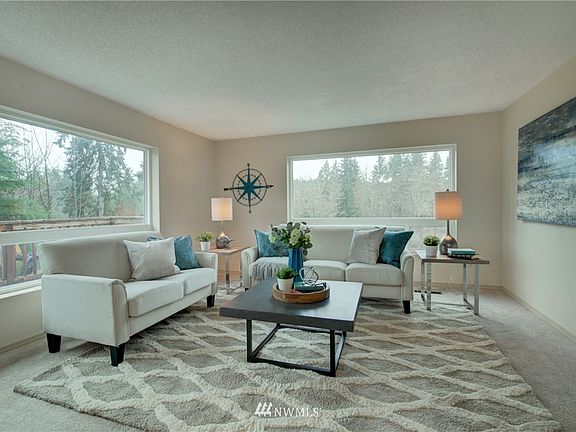 The spacious living room features large picture windows that overlook the property