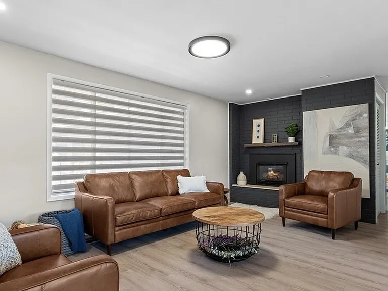 Open living area with large window, comfortable seating, and a fireplace feature wall for relaxing or gathering.