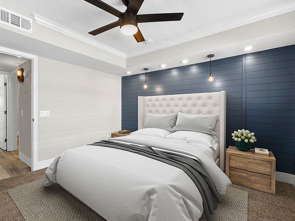 Carpeted bedroom with ceiling fan and textured shiplap accent wall.