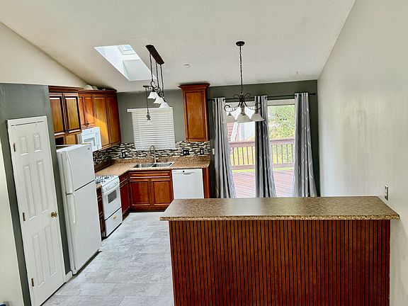 Kitchen open to upstairs living room with small deck behind slider door